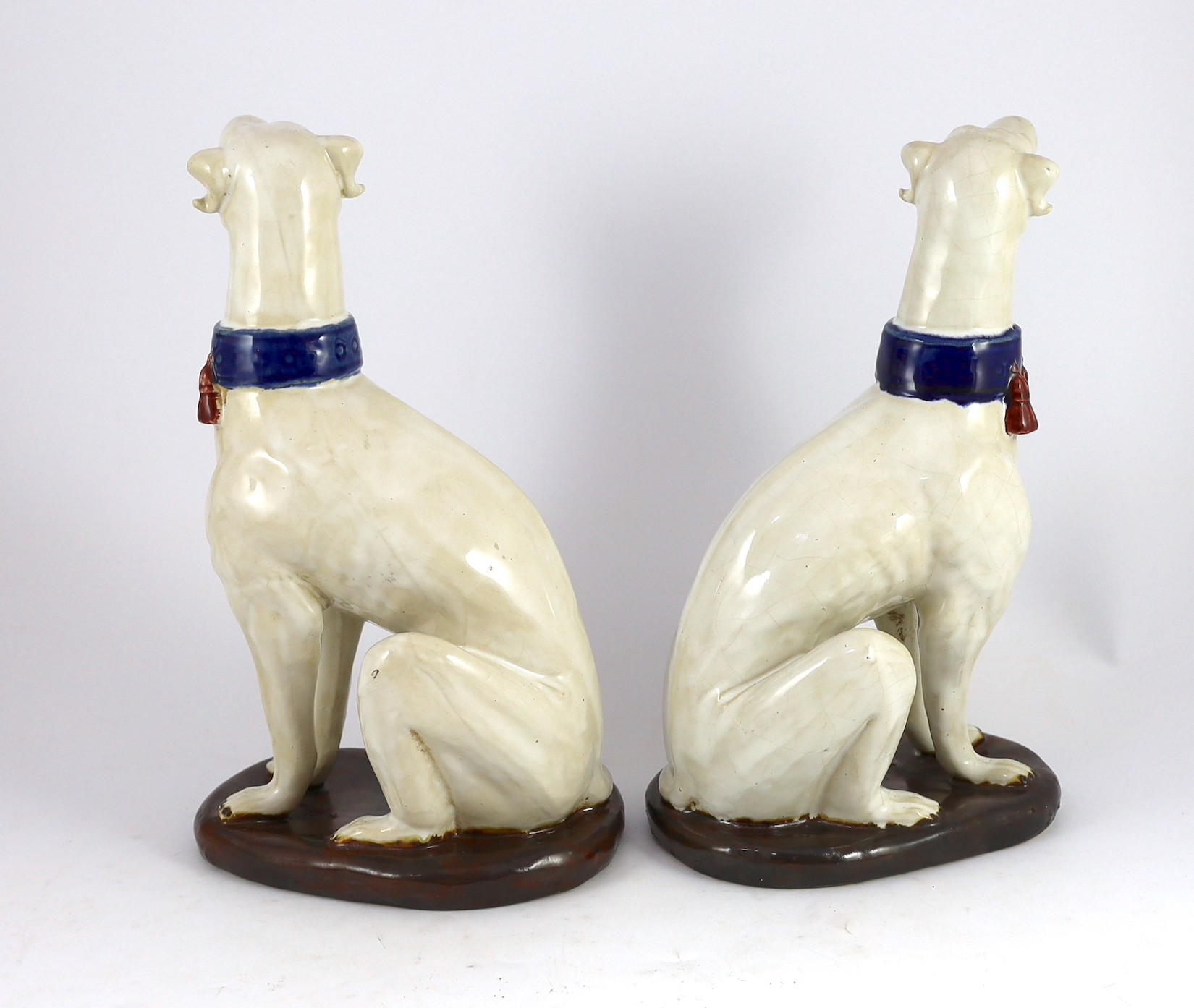 A pair of Italian tin-glaze earthenware figures of seated greyhounds, 35cm high